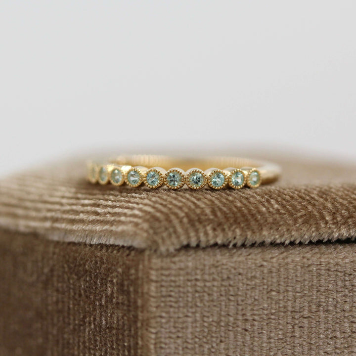 The August Florence Birthstone Wedding Band with Chrysoberyl in Yellow Gold atop of a brown velvet ring box