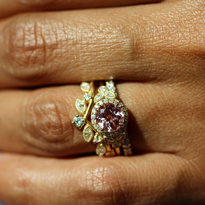 The Cate Ring (Round) in Yellow Gold and Peachy-Pink Created Sapphire stacked with the Clementine Wedding Band in Yellow Gold and the Elizabeth Wedding Band in Yellow Gold modeled on a hand