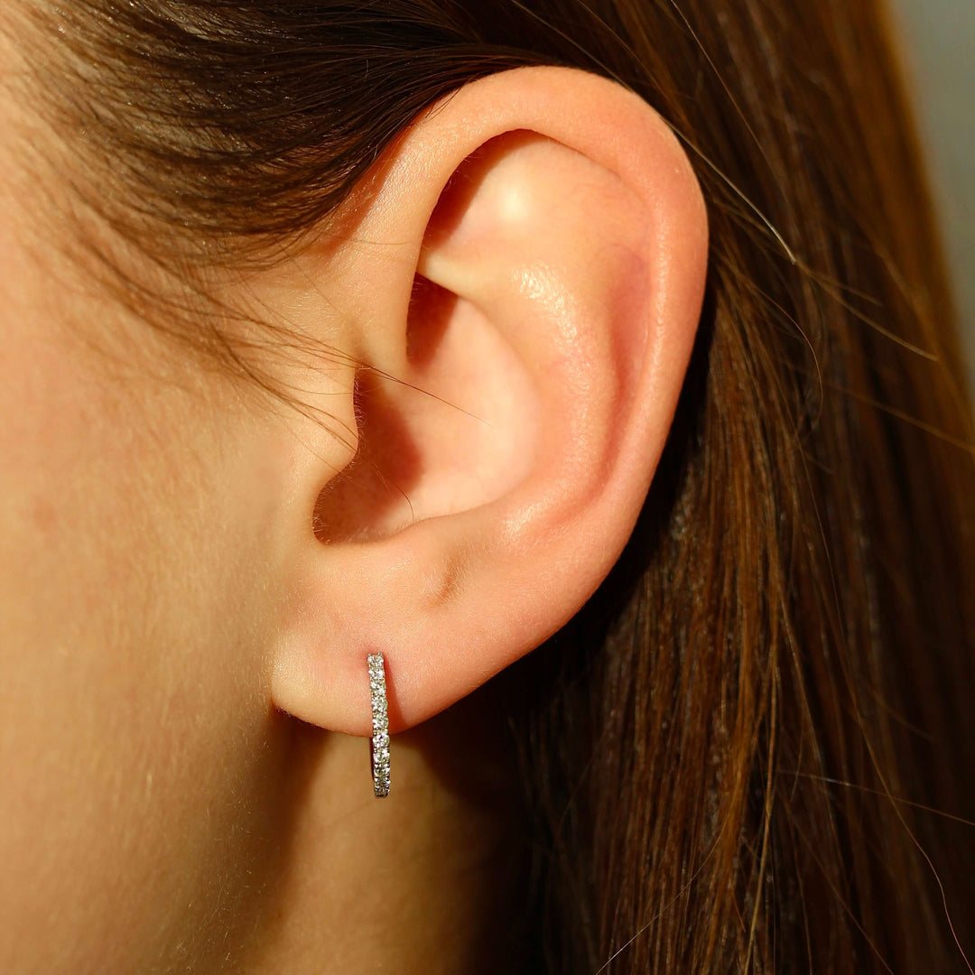The 14mm Diamond Huggies in White Gold modeled on an ear