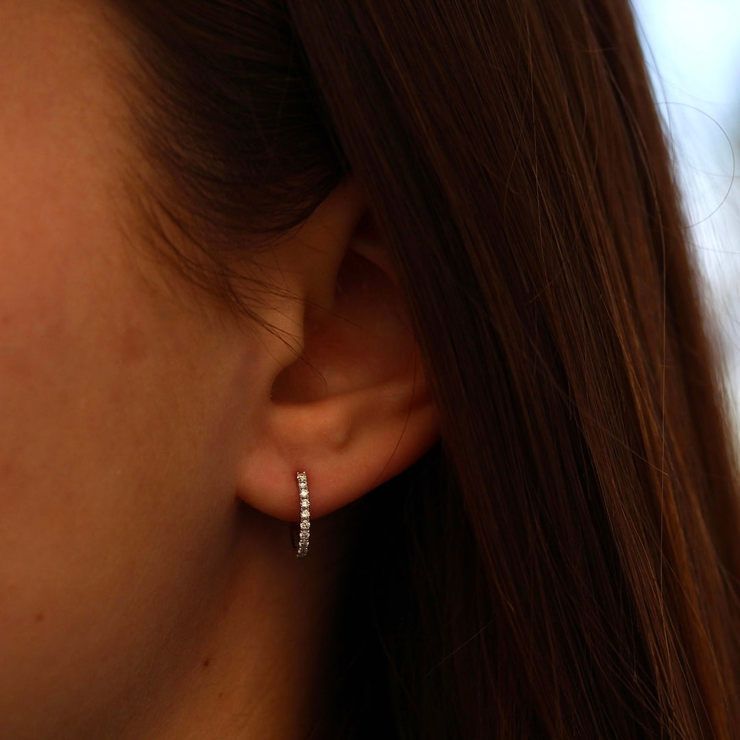 The 14mm Diamond Huggies in White Gold modeled on an ear