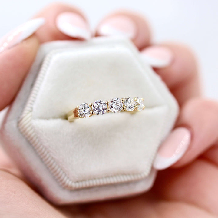 The Elisa Wedding Band in Yellow Gold with 1.25ct Lab-Grown Diamond in a white velvet ring box held by a hand