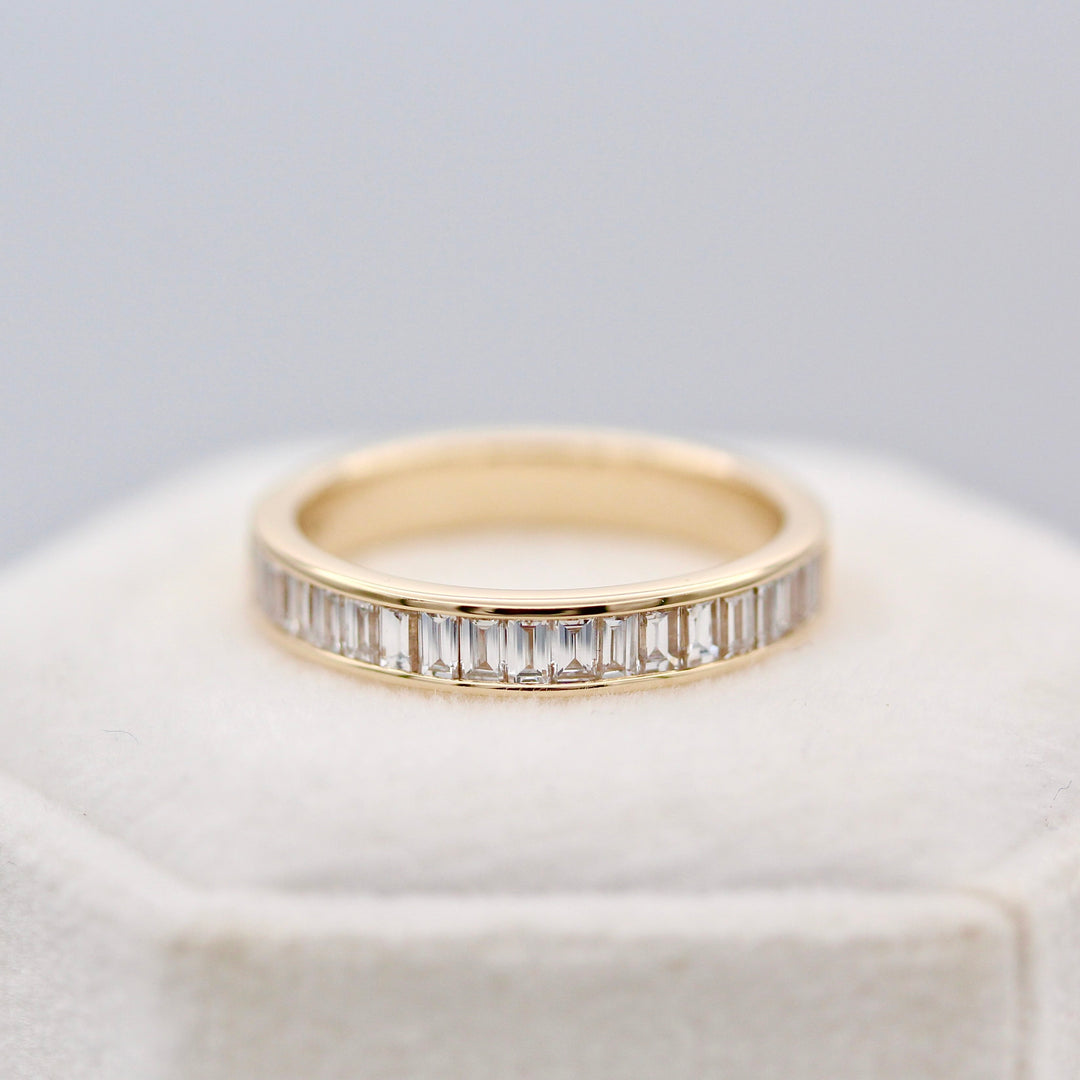 Baguette diamond wedding band in yellow  gold on a white velvet ring box.