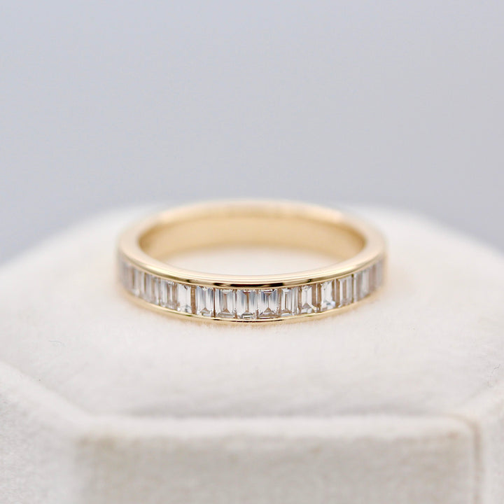 Baguette diamond wedding band in yellow  gold on a white velvet ring box.
