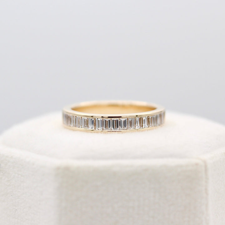 Elle yellow gold baguette diamond ring on top of a white velvet ring box.