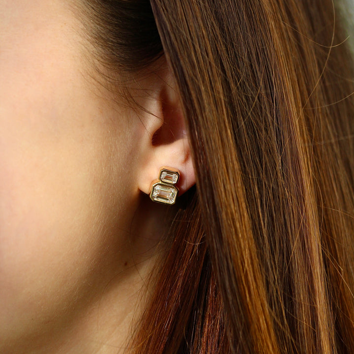 Emerald-Cut Diamond Two-Stone 3.45ct Earrings in Yellow Gold modeled on an ear