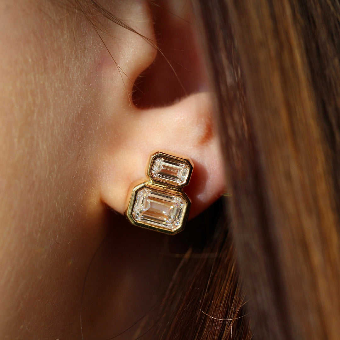 Emerald-Cut Diamond Two-Stone 3.45ct Earrings in Yellow Gold modeled on an ear