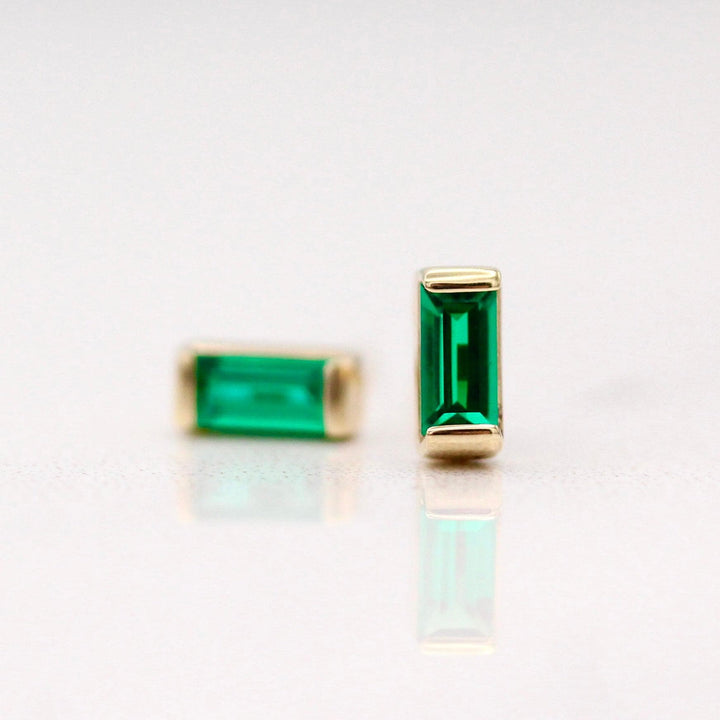 The May Baguette Birthstone Earrings with Emerald in Yellow Gold against a white background