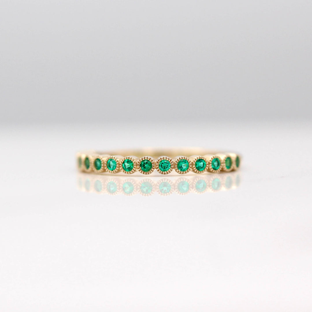 The May Florence Birthstone Wedding Band with Emerald in Yellow Gold against a white background