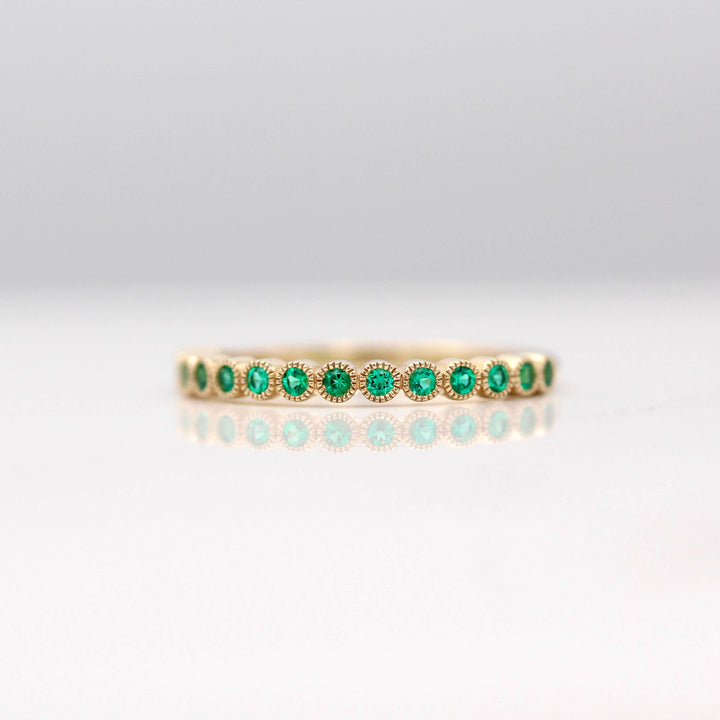The May Florence Birthstone Wedding Band with Emerald in Yellow Gold against a white background
