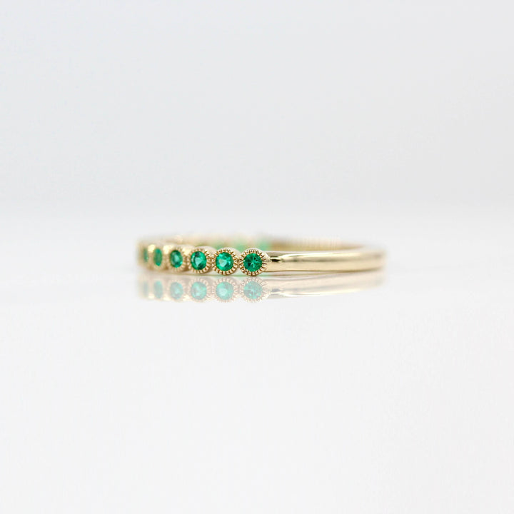 The May Florence Birthstone Wedding Band with Emerald in Yellow Gold against a white background