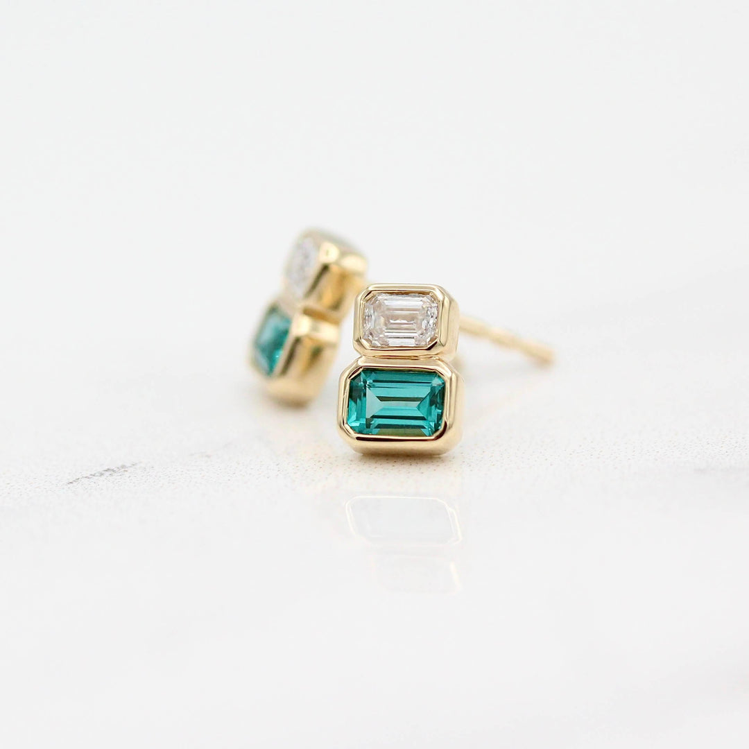 The Emerald-Cut Diamond and Paraiba Spinel Two-Stone Earrings in Yellow Gold against a white background