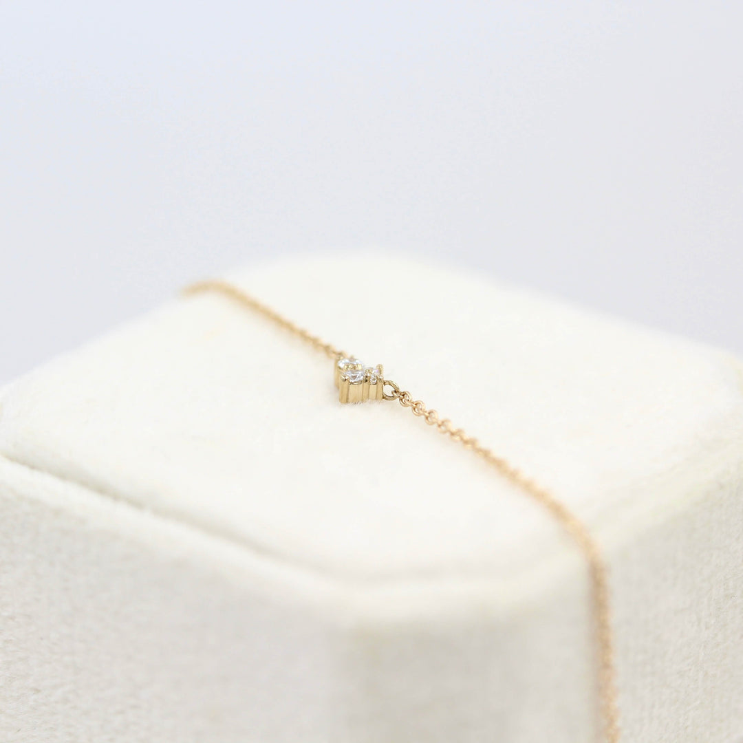 The Felicity Necklace in yellow gold atop a white velvet ring box