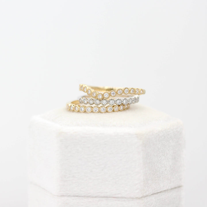The Florence Wedding Band in Yellow Gold and the Florence Contour Wedding Band in Yellow Gold stacked with the Florence Wedding Band in White Gold atop a ring box