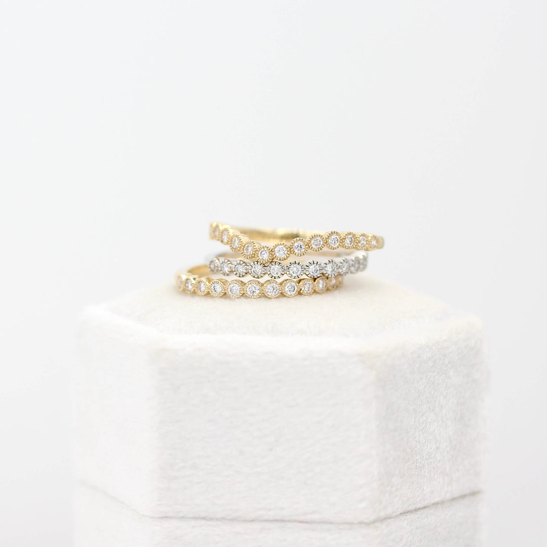 The Florence Wedding Band in Yellow Gold and the Florence Contour Wedding Band in Yellow Gold stacked with the Florence Wedding Band in White Gold atop a ring box