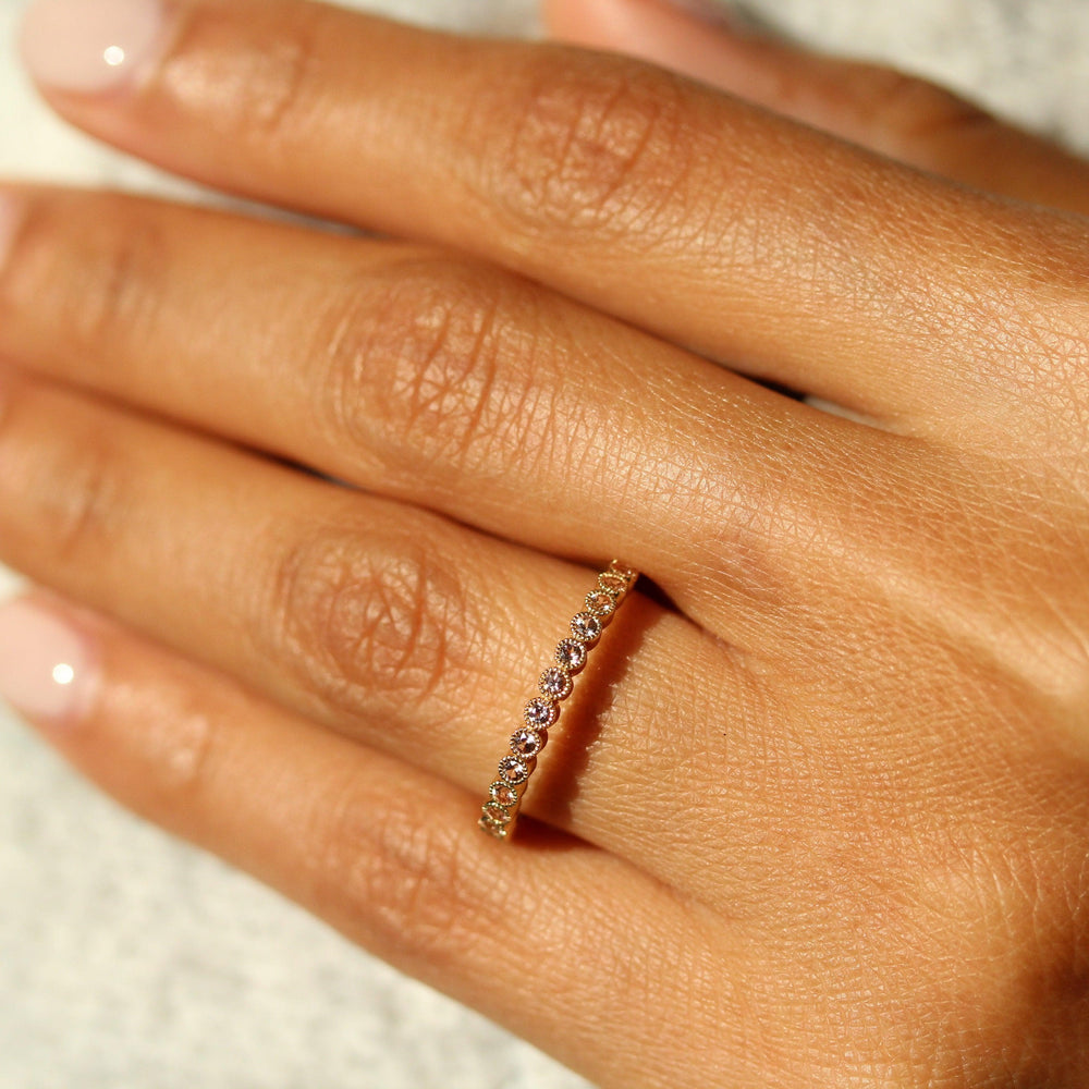 The October Florence Birthstone Wedding Band with Peachy-Pink Sapphire in Yellow Gold modeled