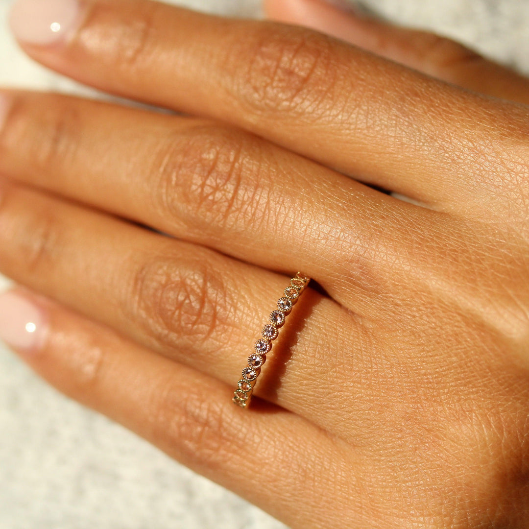 The October Florence Birthstone Wedding Band with Peachy-Pink Sapphire in Yellow Gold modeled