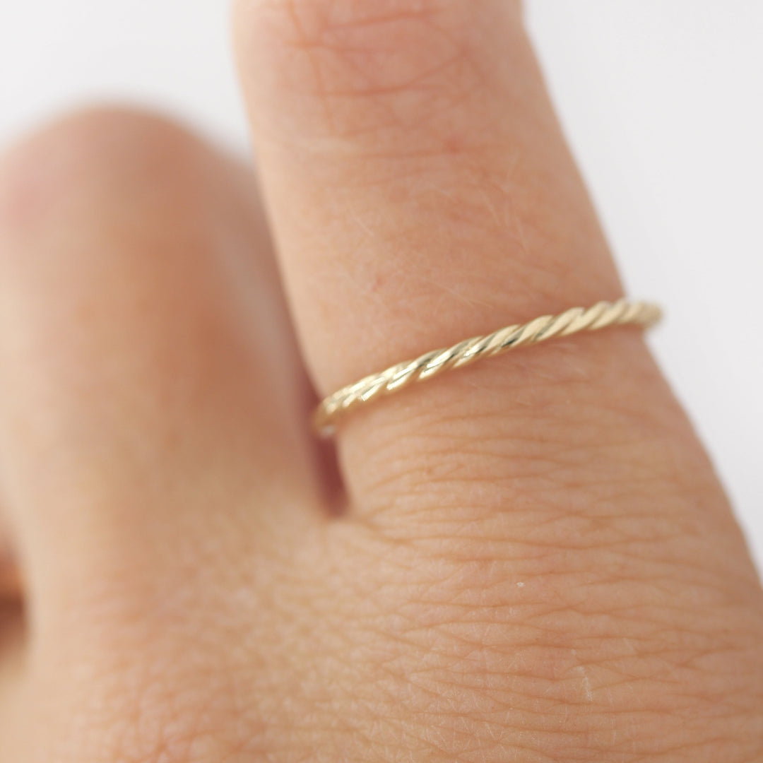 Hand wearing dainty gold twist stacking band