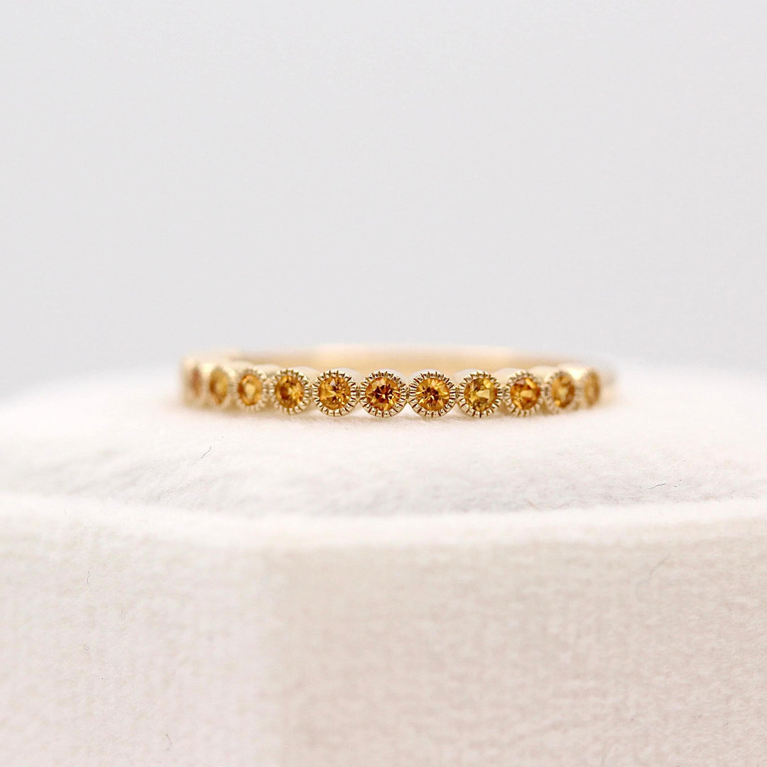 The November Florence Birthstone Wedding Band with Gold Sapphire in Yellow Gold atop of a white velvet ring box