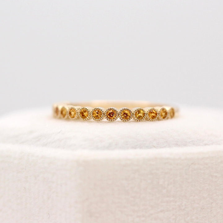 The November Florence Birthstone Wedding Band with Gold Sapphire in Yellow Gold atop of a white velvet ring box