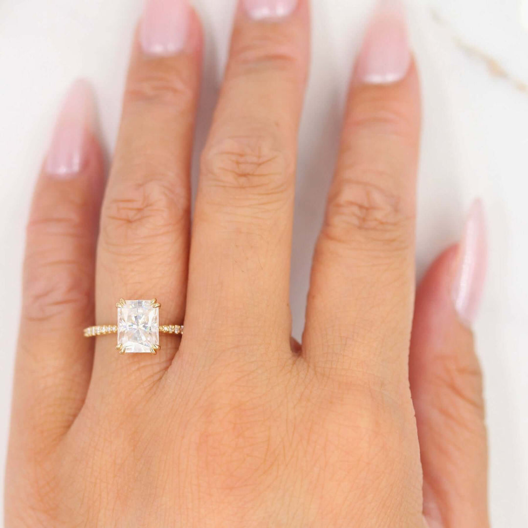 Hand showing off radiant moissanite engagement ring with vintage details