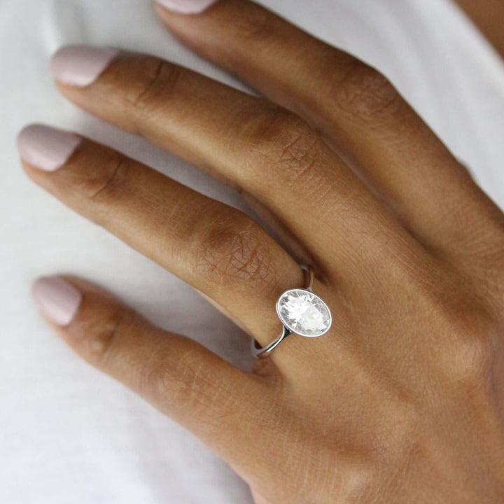 14k white gold 2ct oval moissanite bezel solitaire engagement ring modeled on a hand