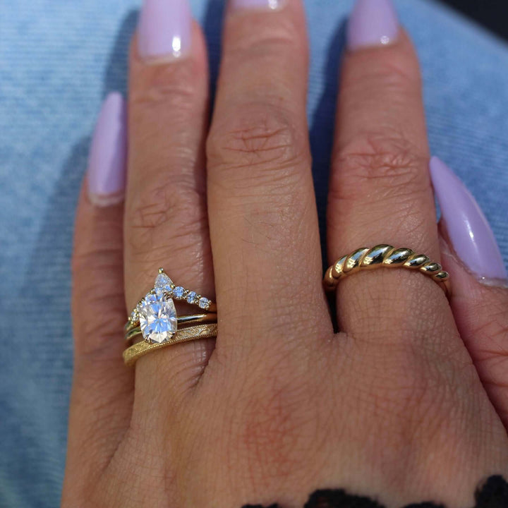 Hand wearing Serena elongated cushion solitaire engagement ring with Tiara and Sabrina wedding bands and the Petite Croissant ring