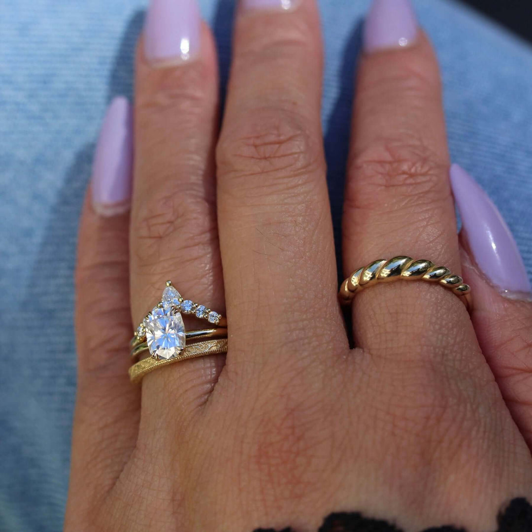 Hand wearing Serena elongated cushion solitaire engagement ring with Tiara and Sabrina wedding bands and the Petite Croissant ring