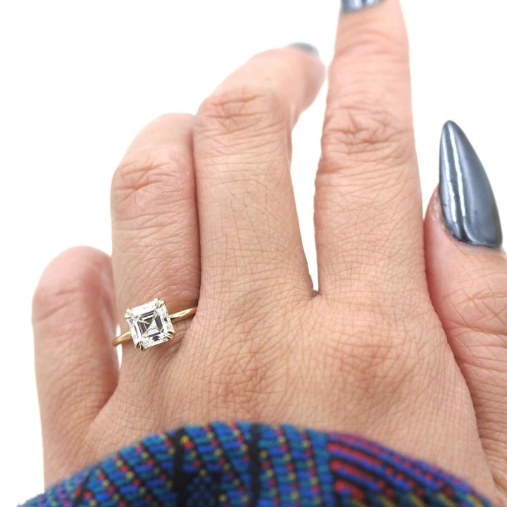 Hand wearing asscher moissanite solitaire engagement ring