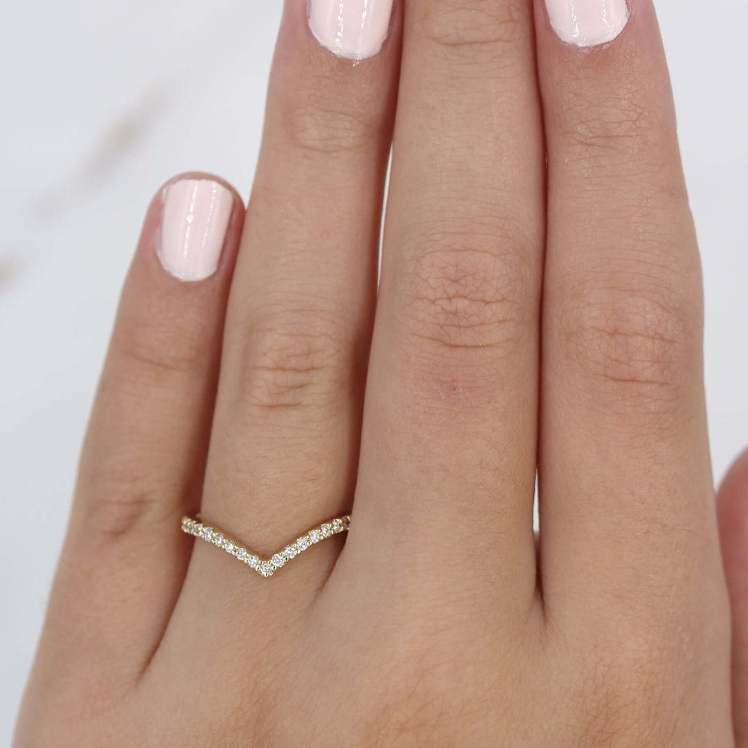 Hand wearing v-shaped lab-grown diamond wedding band in yellow gold