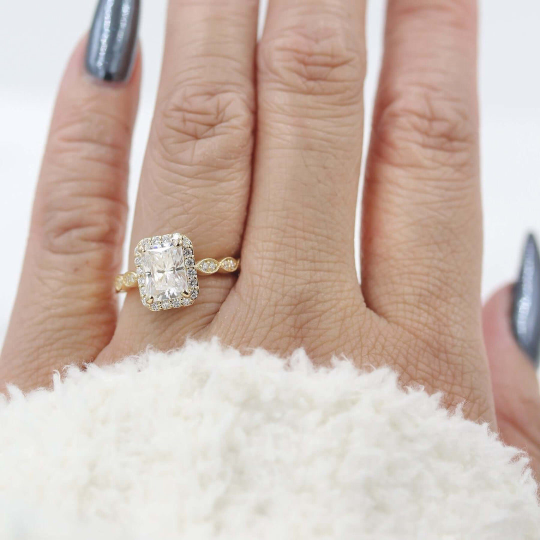 Hand wearing vintage-inspired radiant halo engagement ring