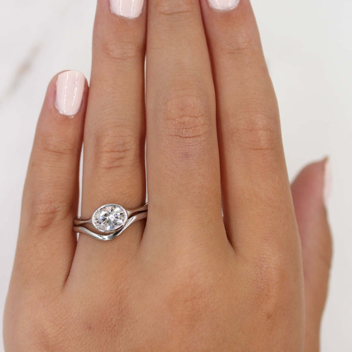 The Stevie Ring (East-West Oval) in White Gold stacked with the Wave wedding band in white gold modeled on a hand