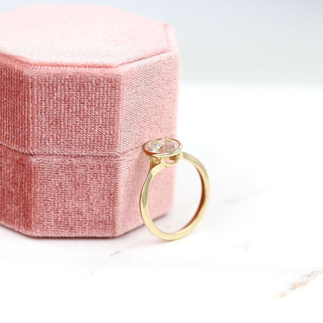The Stevie Ring (Oval) in Yellow Gold with Lab Grown Diamond against a pink velvet ring box