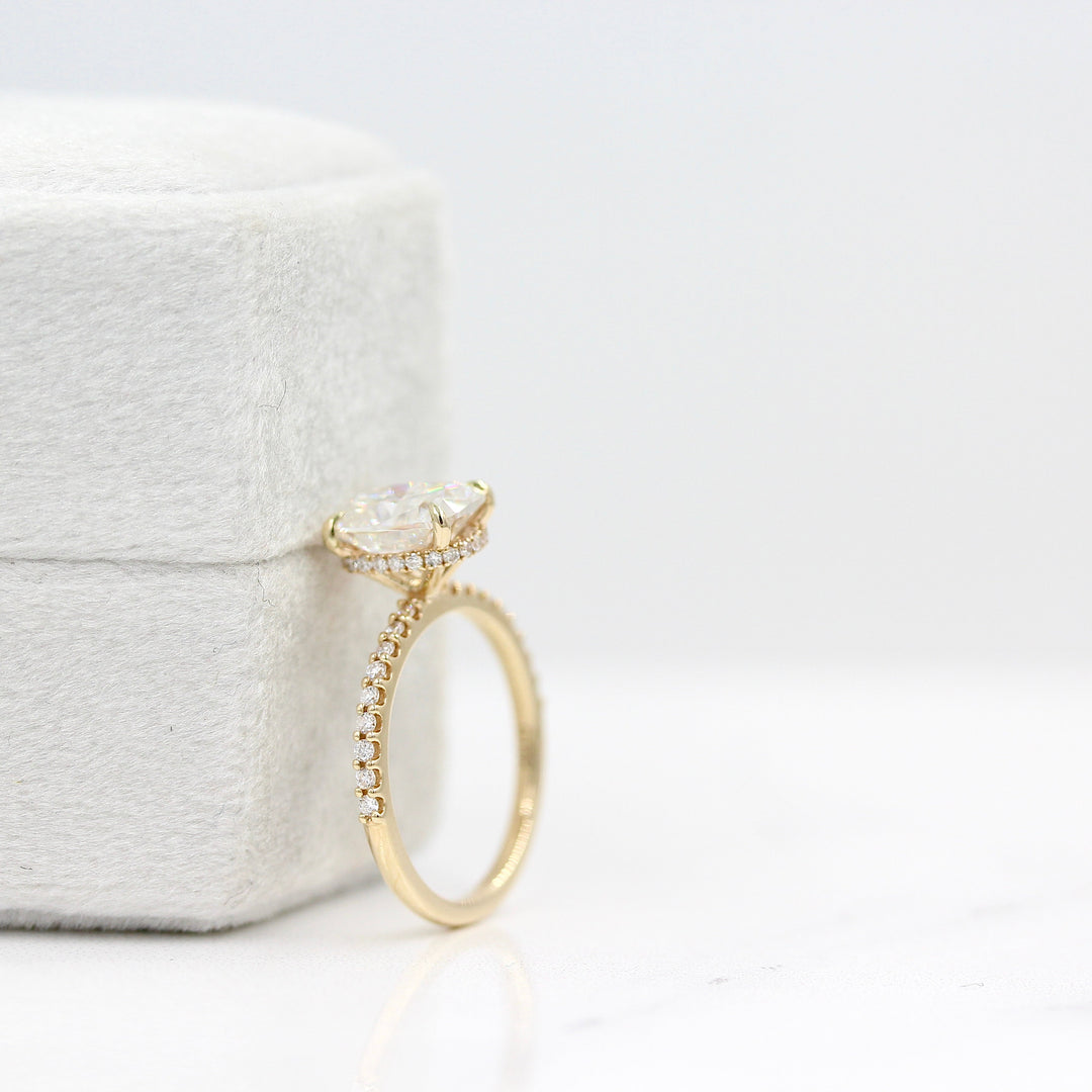 The Paris Hidden Halo Ring in Yellow Gold with 2ct Moissanite leaning against a white velvet ring box
