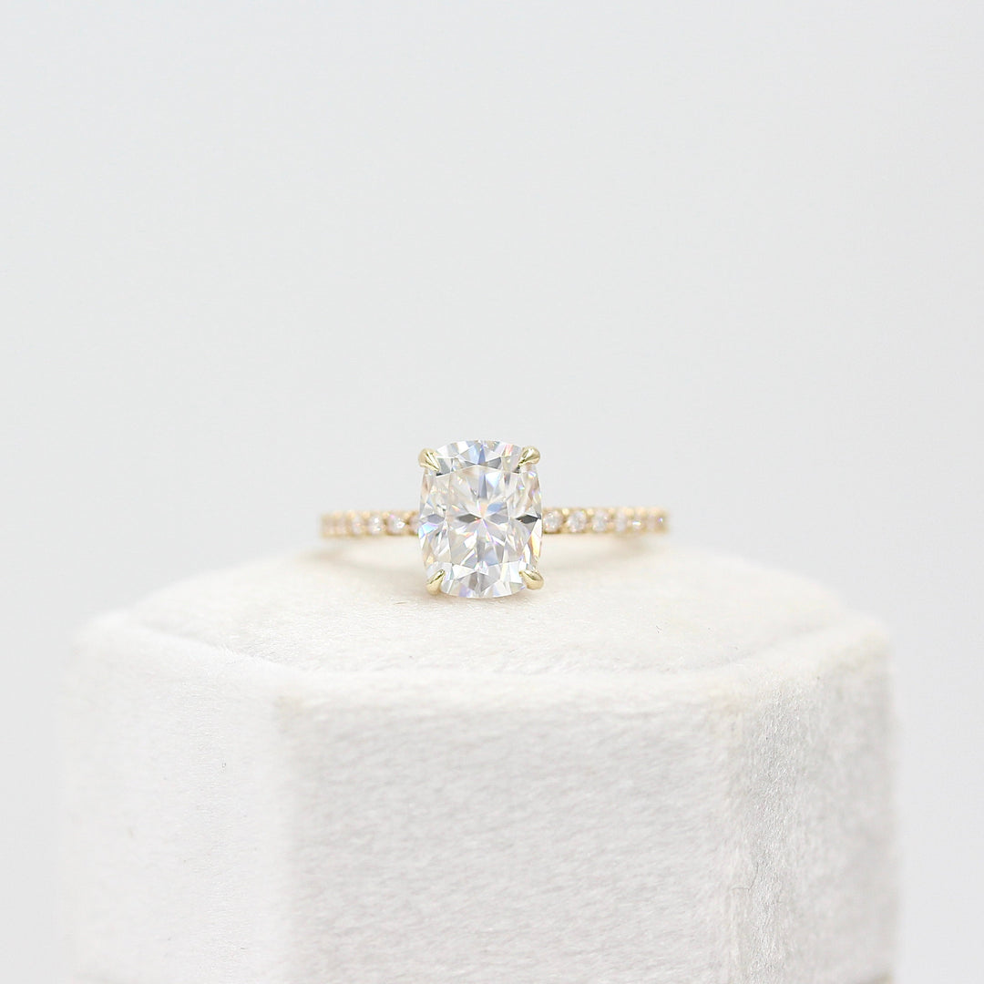 The Paris Hidden Halo Ring (Cushion) in yellow gold leaning in a white velvet ring box