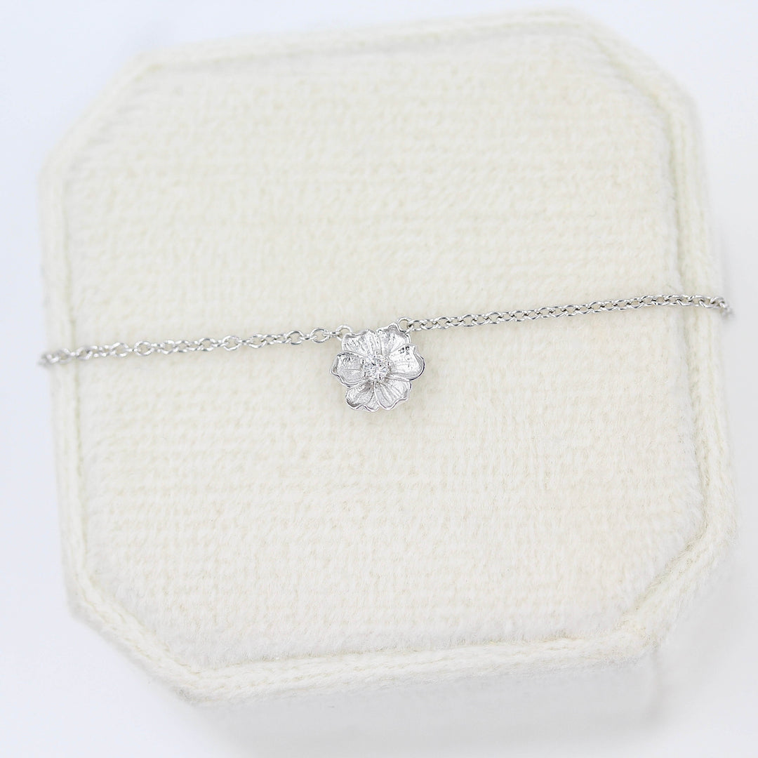The Poppy Necklace in White Gold against a tan velvet ring box