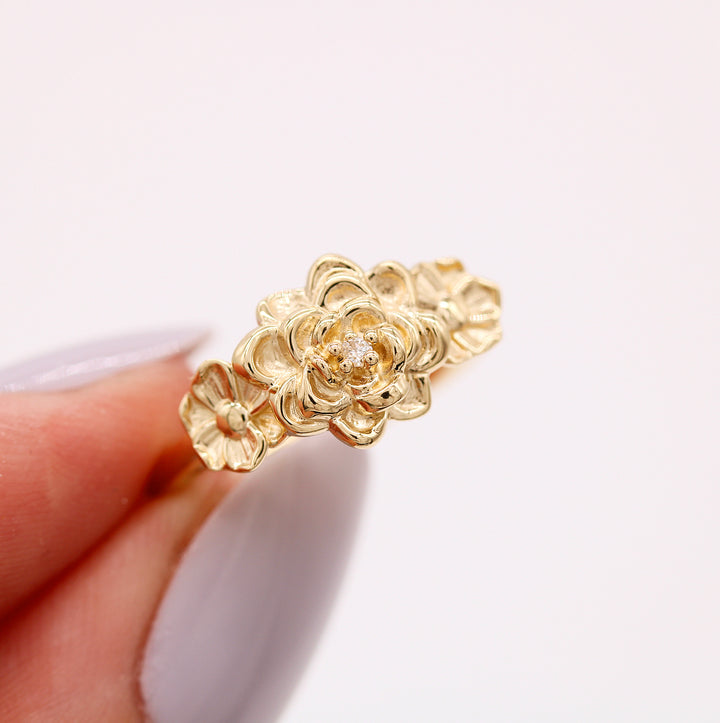 The Posy ring in yellow gold held by a hand