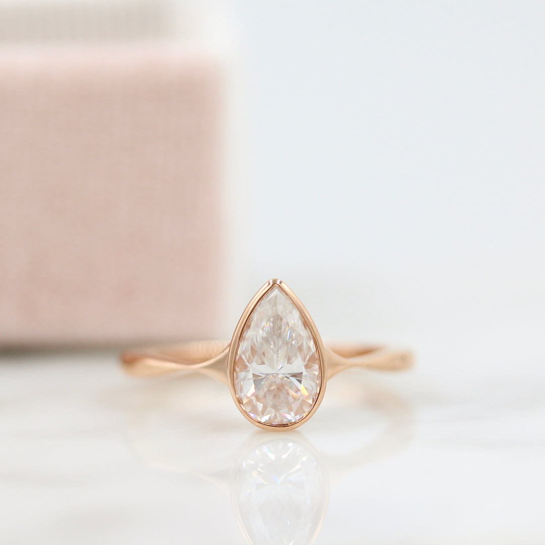 Stevie ring (pear) in rose gold in front of a pink ring box