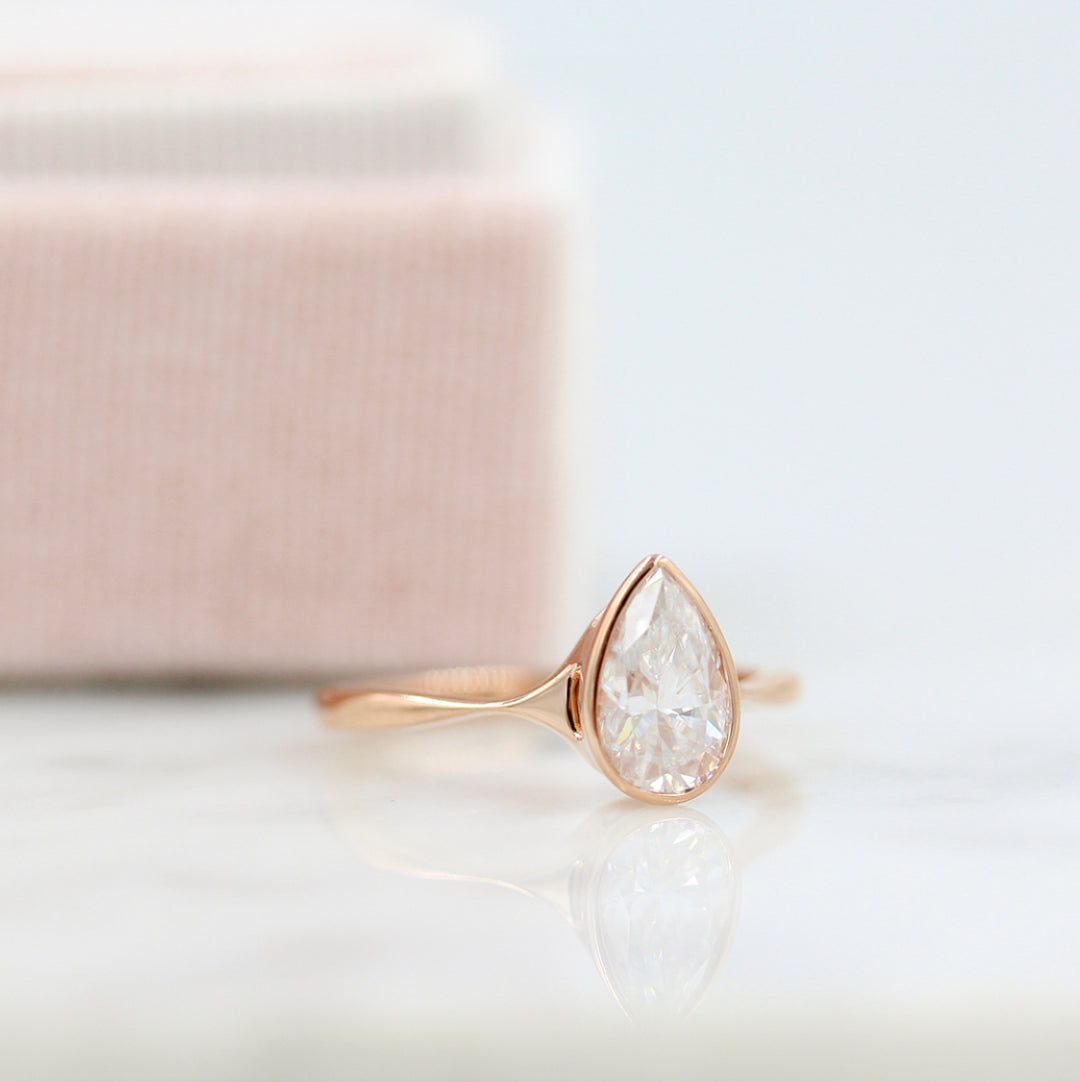 Stevie ring (pear) in rose gold in front of a pink ring box