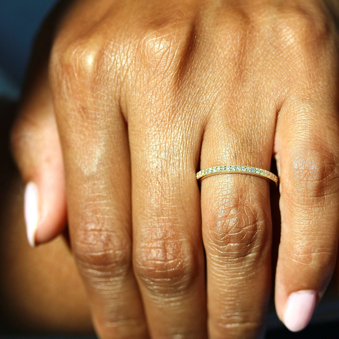 The Amber Wedding Band in Yellow Gold modeled on a hand