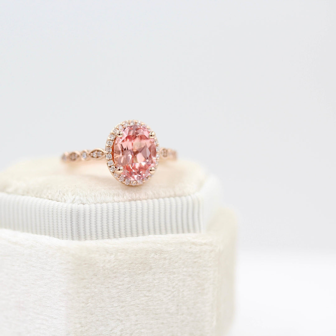 The Charlotte Ring with Peachy-Pink Created Sapphire in rose gold atop a white velvet ring box