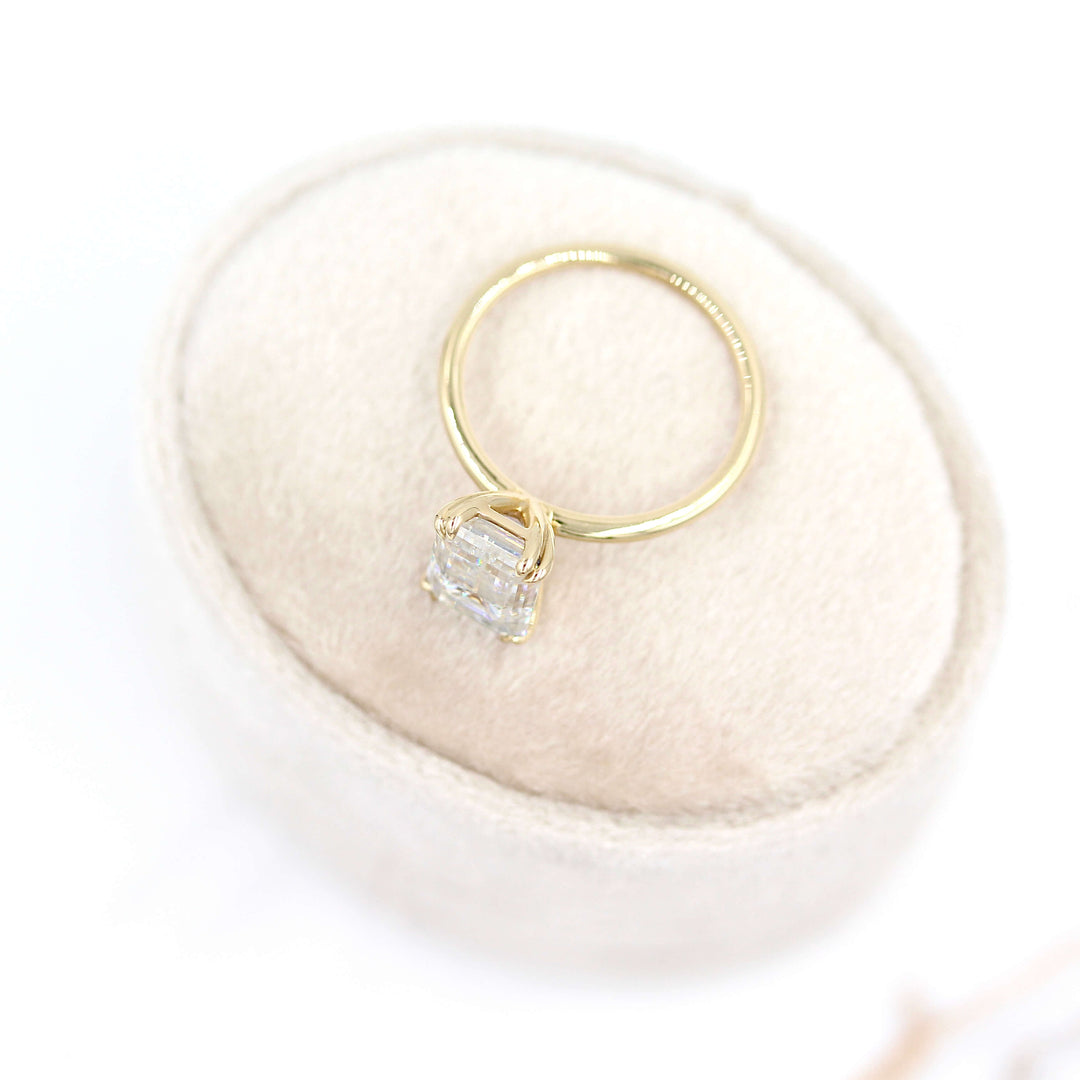 The Serena Ring (Emerald) in Yellow Gold and Moissanite on a tan velvet ring box