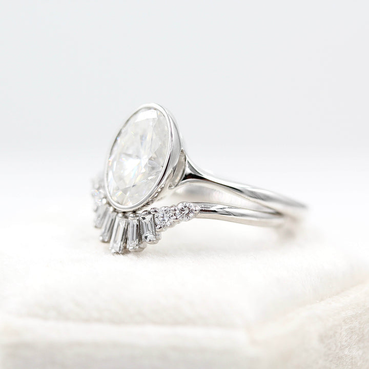 The Sunburst Wedding Band in white gold stacked with the Stevie Oval ring in white gold against a white velvet ring box