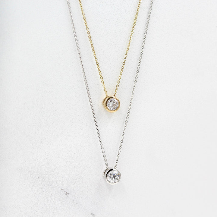1/2ct Diamond Bezel Necklace in Yellow Gold and the 1/2ct Diamond Bezel Necklace in White Gold against white background