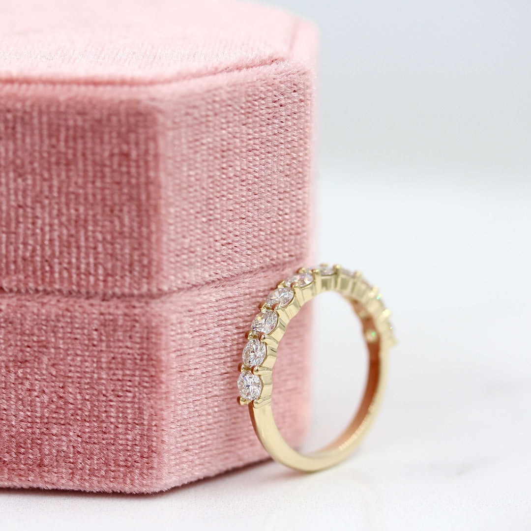 The Lexington Wedding Band in Yellow Gold leaning against a pink velvet ring box