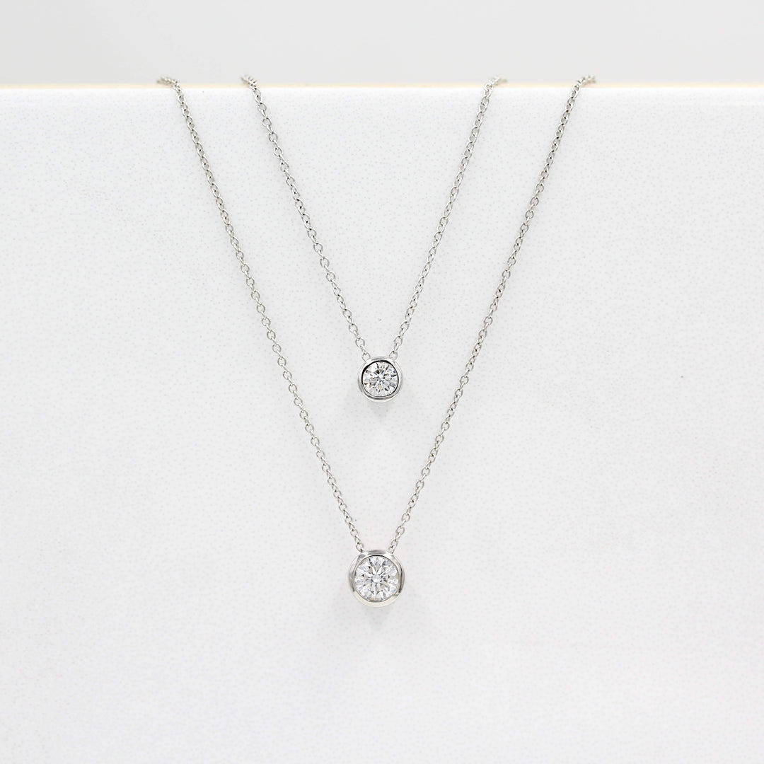 1/2ct Diamond Bezel Necklace in White Gold and the 1/4ct Diamond Bezel Necklace in White Gold against a white background