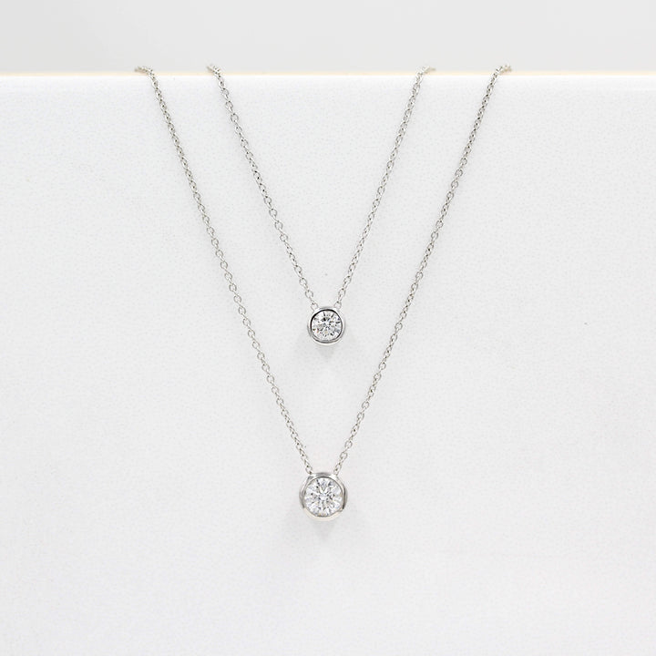 1/2ct Diamond Bezel Necklace in White Gold and the 1/4ct Diamond Bezel Necklace in White Gold against a white background