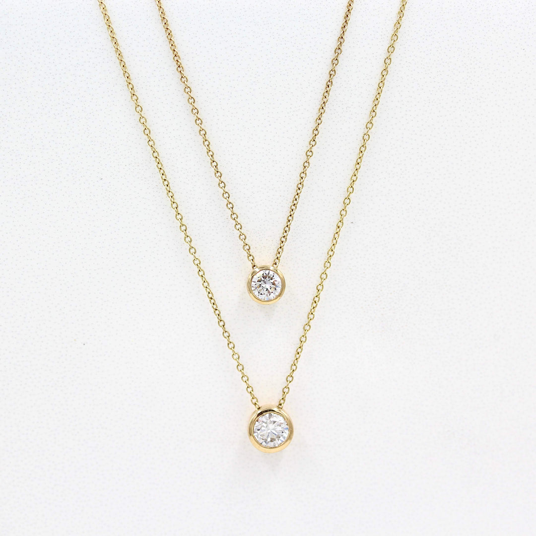 1/2ct Diamond Bezel Necklace in Yellow Gold and the 1/4ct Diamond Bezel Necklace in Yellow Gold against a white background