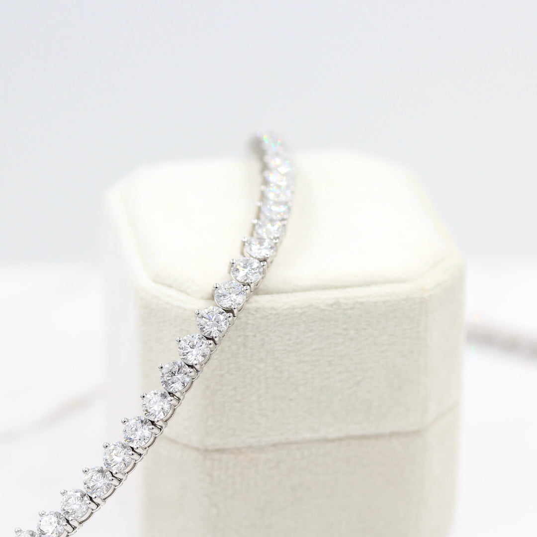 The Lab Grown Diamond Tennis Necklace in white gold draped over a tan velvet ring box