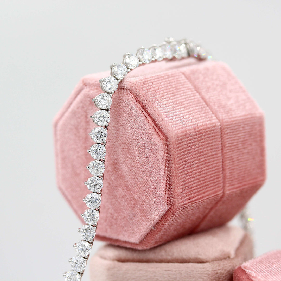 The Lab Grown Diamond Tennis Necklace in white gold draped over three pink velvet ring boxes