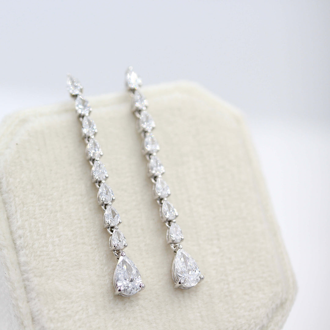 Pear Drop Earrings in white gold draped over a tan velvet ring box